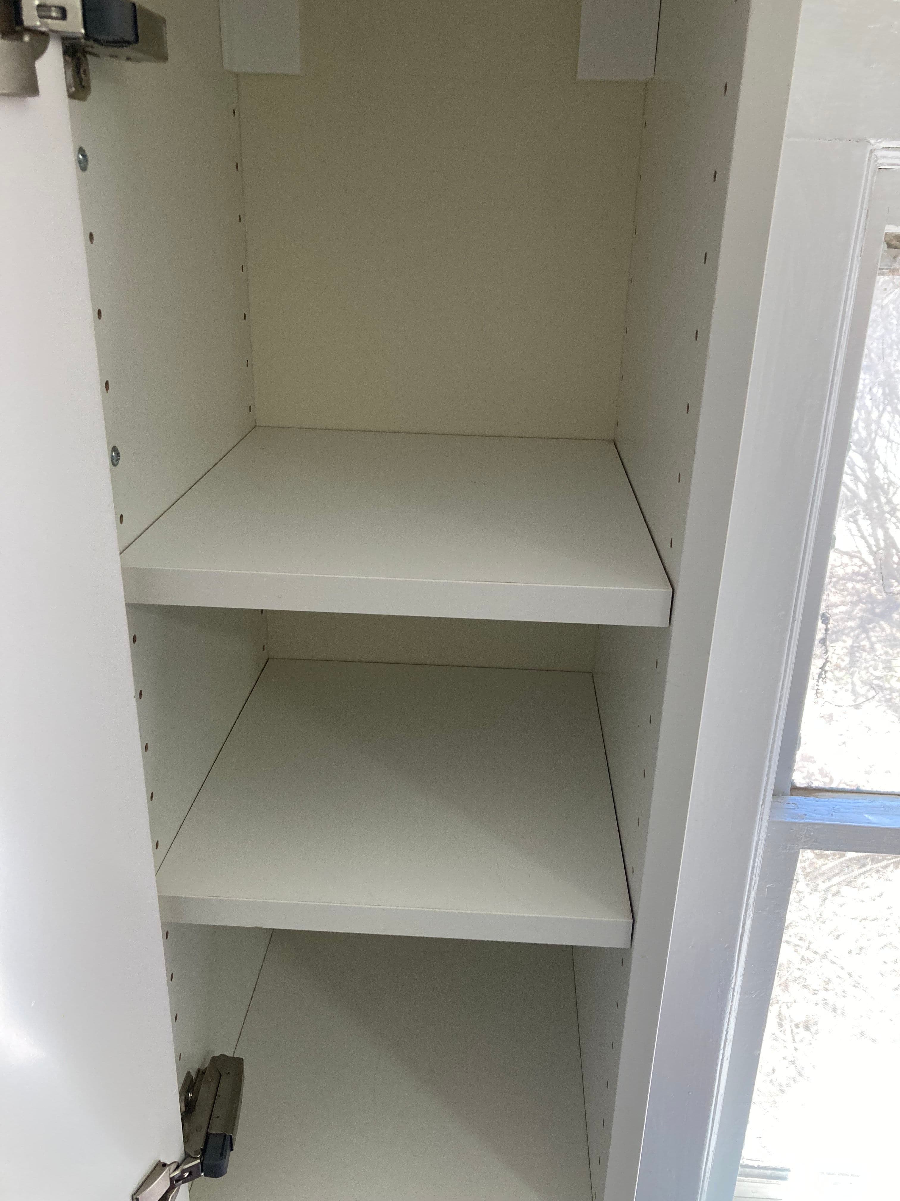 Empty white cabinet with adjustable shelves and a closed door, featuring a lock.
